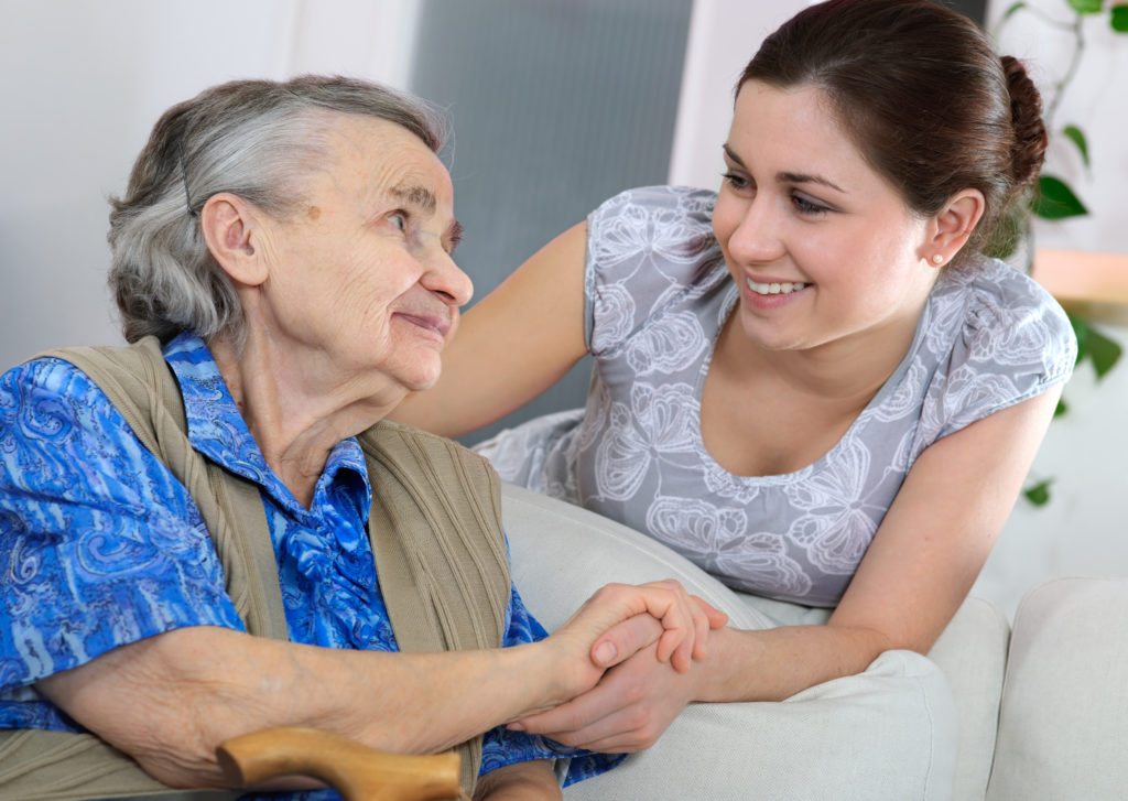 Senior woman with her home young caregiver